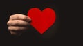 Hand holding paper heart on black background. Health insurance, organ donor day, charity. World health day, world mental Royalty Free Stock Photo