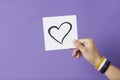 Hand holding a paper with a heart wearing a non binary gender flag bracelet Royalty Free Stock Photo