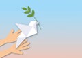 Hand holding paper white dove or pigeon carrying olive branch flying on pastel background, Concept for International Day of Peace Royalty Free Stock Photo