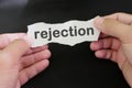 Hand holding a paper with written word rejection in black background. How to handle rejection concept.