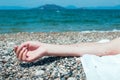 Hand holding pebbles on a beach, turquoise sea water in the back Royalty Free Stock Photo