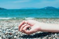 Hand holding pebbles on a beach, turquoise sea water in the back Royalty Free Stock Photo