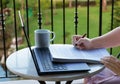 hand holding pen over paperwork with laptop on balcony Royalty Free Stock Photo