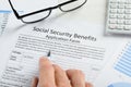 Hand holding pen over social security benefits form