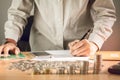 Business hand holding a pen on the table with a medal recognizing computation and Sunset light Business Background.