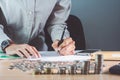 Business hand holding a pen on the table with a medal recognizing computation and Sunset light Business Background.