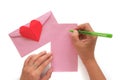 Hand holding a pen and writing a letter with red heart paper origami and pink envelope Royalty Free Stock Photo