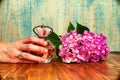 Hand holding a perfume and hydrangea wooden background