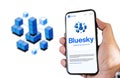 hand holding a phone with Bluesky mobile app on screen