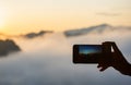 Hand holding the phone shooting the morning sun and the fog