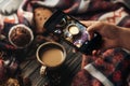 hand holding phone taking photo of stylish winter flat lay coffee cookies and spices on wooden rustic background. cozy mood