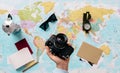 Hand holding a photo camera with a world map in the background next to a compass, sunglasses, notepad, compass and an Italian Royalty Free Stock Photo