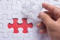 Hand holding piece of blank jigsaw puzzle with red background Royalty Free Stock Photo