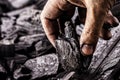 hand holding piece of charcoal, with background. Dirty coal emitter hand, MACRO PHOTOGRAPHY