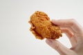 A hand holding a piece of crispy fried chicken with a perfectly golden crust.