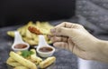 Hand holding piece of french fries with ketchup, selective focus. Royalty Free Stock Photo