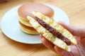 Hand Holding a Piece of Half Dorayaki with Stack of Whole Cake on Wooden Table Royalty Free Stock Photo