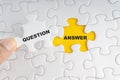 Hand holding piece of jigsaw puzzle with word ANSWER QUESTION Royalty Free Stock Photo