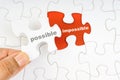 Hand holding piece of jigsaw puzzle with word POSSIBLE IMPOSSIBLE