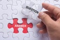 Hand holding piece of jigsaw puzzle with word question & answer. Royalty Free Stock Photo