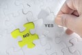 Hand holding piece of jigsaw puzzle with word YES NO. Royalty Free Stock Photo