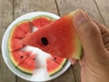 Hand holding a piece of sliced ripe watermelon.