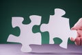 Hand holding piece of white puzzle on green background Royalty Free Stock Photo