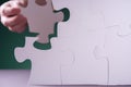 Hand holding piece of white puzzle on green background Royalty Free Stock Photo