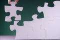 Hand holding piece of white puzzle on green background Royalty Free Stock Photo