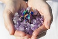 A hand holding a pile of amethyst and a rainbow titanium aura piece Royalty Free Stock Photo