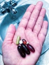 Hand holding pills and vitamins in palm.