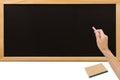 Hand holding pink chalk in front of a blank blackboard. Royalty Free Stock Photo