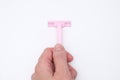 A hand holding pink disposable plastic woman razor blade for shaving, body care and unwatred hair removing on legs Royalty Free Stock Photo