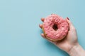 Hand Holding Pink Donut on Blue Background