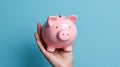 Hand holding a pink piggy bank on blue background. Generative AI Royalty Free Stock Photo