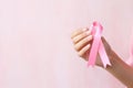 Hand holding a pink ribbon, a universal symbol of breast cancer awareness and personal support