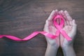 hand holding pink ribbon on wood. breast cancer awareness. conc