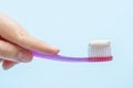Hand holding pink toothbrush with toothpaste on a blue background close-up, side view. Royalty Free Stock Photo