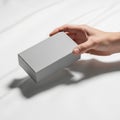 A hand holding a plain rectangular gray box against a smooth white background Royalty Free Stock Photo