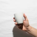 A hand holding a plain white ceramic cup against a white backgroun Royalty Free Stock Photo