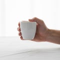 A hand holding a plain white ceramic cup against a white background Royalty Free Stock Photo