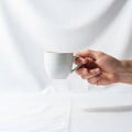 A hand holding a plain white ceramic cup with fingers gripping the handle Royalty Free Stock Photo
