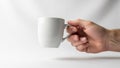 A hand holding a plain white ceramic mug against a neutral white backgroun Royalty Free Stock Photo