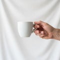 A hand holding a plain white ceramic mug against a simple white Royalty Free Stock Photo