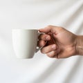 A hand is holding a plain white ceramic mug against a soft white Royalty Free Stock Photo