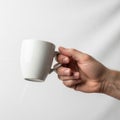 A hand is holding a plain white ceramic mug against a white backgroun Royalty Free Stock Photo