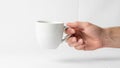 A hand is holding a plain white ceramic mug against a white background Royalty Free Stock Photo