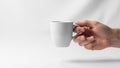 A hand is holding a plain white ceramic mug against a white background Royalty Free Stock Photo