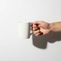 A hand holding a plain white ceramic mug against a white background Royalty Free Stock Photo