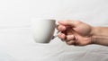 Hand holding a plain white ceramic mug by the handle against a Royalty Free Stock Photo